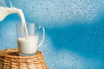 Glass of milk and jug on wooden background