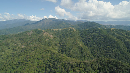 Aerial view of mountains covered with green forest, trees with blue sky. Slopes of mountains with tropical forest. Philippines, ,Luzon. Tropical landscape in Asia.