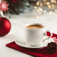 Cup of espresso or americano coffee in white cup in cozy Christmas arrangement, festive decoration with bokeh background, copy space