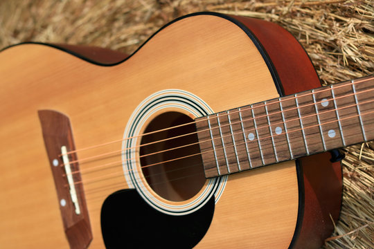 Close up of an acoustic guitar in a wheat field