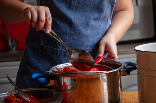 woman cook prepares tomatoes in a saucepan, rubs through a sieve and prepares tomato juice. Female hands closeup.