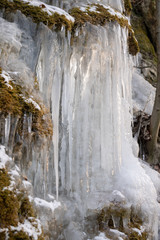 Icicles of an overfrozen spring dripping down a limestone cliff