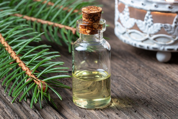 A bottle of spruce essential oil with fresh spruce branches