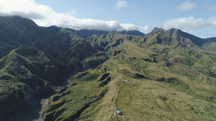 Fototapeta premium Aerial view of mountains covered with green vegetation, trees in vicinity volcano Pinatubo. Slopes of mountains, sky and clouds. Cordillera region. Luzon, Philippines.