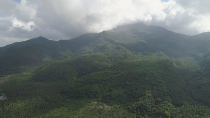 Aerial view of mountains covered forest, trees in cloudy weather, Bulusan Volcano. Luzon, Philippines. Slopes of mountains with evergreen vegetation. Mountainous tropical landscape.