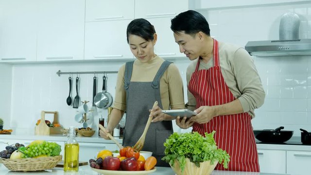 Asian couple cooking food together at home. Husband and wife enjoying when having time to prepare dinner.
