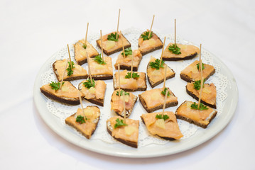 Smoked salmon canapes on a white plate over white background, cl