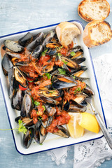 Traditionelle italienische gegrillte Miesmuscheln mit Weißbrot und Tomaten Sauce in Weißwein als Draufsicht in einer weißen Bratreine