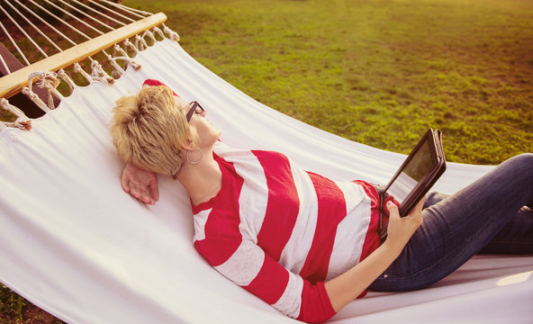 woman using a tablet computer while relaxing on hammock