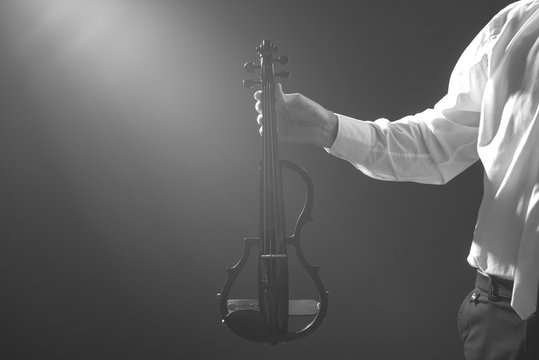 The musician holds a electronic violin in his hands   