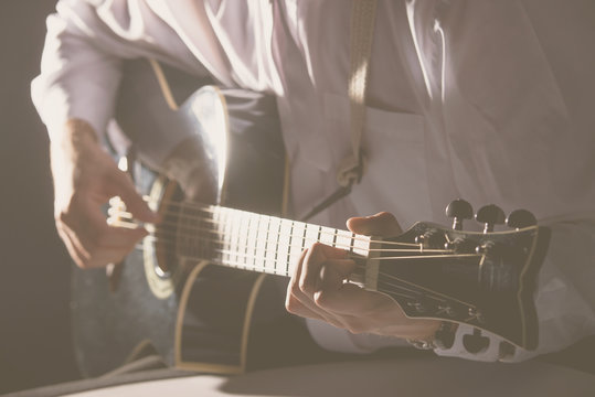 Musician plays guitar hands on strings close up