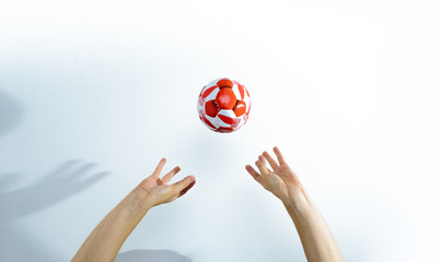 Hands hit the red ball. Front view of hands raised on a reflecting ball against a bright white...