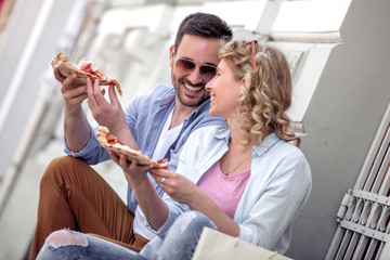 Happy  couple eat pizza outdoors