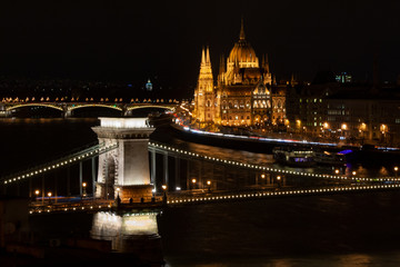 Fototapeta na wymiar Budapest, Ungarn., Kettenbrücke über die Donau, im Hintergrund das monumentale Parlamentsgebäude bei Nacht mit Beleuchtung neben der Donau