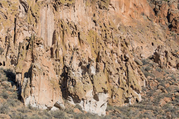 Unusual, colorful tufa rock formations and cliffs with a confusing pattern of eroded holes and small caves in Bandelier National Monument near Santa Fe, New Mexico
