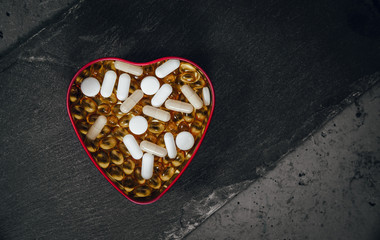 Top view of a heart shaped box filled with various tablets. Medical and health concept, health and...