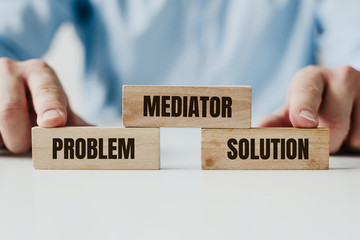 Hand holding a wooden jigsaw puzzle with conflict and Mediator word. There is a matching puzzle next to it. The concept of solving problems, all problems can be solved, connection.