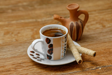 Small coffee with milk and cookie on old wooden table