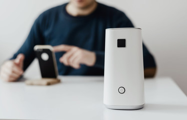 White ionizer is standing on a white table in the background of a working man. Concept of caring for fresh air in the apartment, in the office. Caring for well-being and health. Air filter.