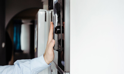A man dressed in a business shirt puts a dish into the oven and microwave. Concept of cooking by men, turning on the oven for preparing meals. Men cooking at home, using an oven.
