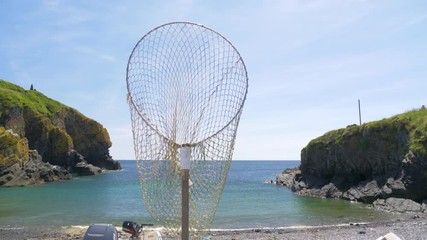 A fishing net flapping in the wind, on Cadgwith Cove beach, Cornwall.