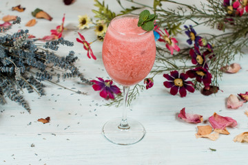 Fresh fruit cocktail on white texture table with herbs and frobers on background