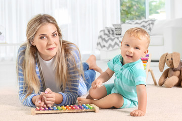 Naklejka premium Baby and mother playing with toy xylophone at home