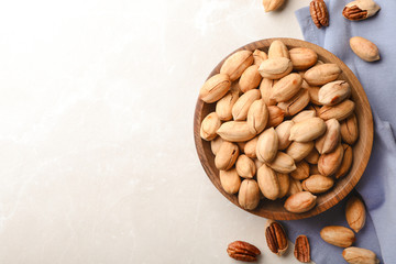 Ripe pecan nuts in dish served on light table, flat lay. Space for text