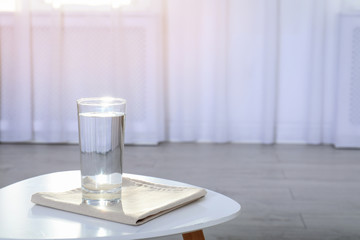 Glass of water on table against blurred background. Space for text