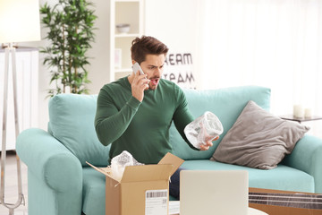 Young man making call about delivered parcel at home