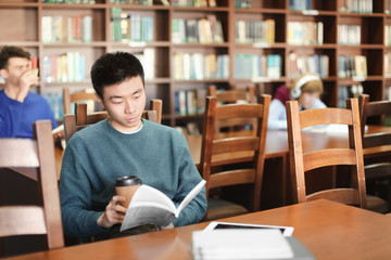 Asian student with book studying in library