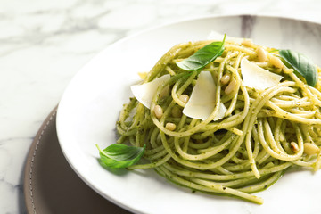 Plate with delicious basil pesto pasta on table, closeup