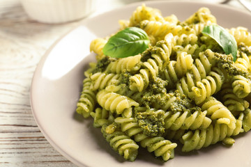 Plate with delicious basil pesto pasta on table