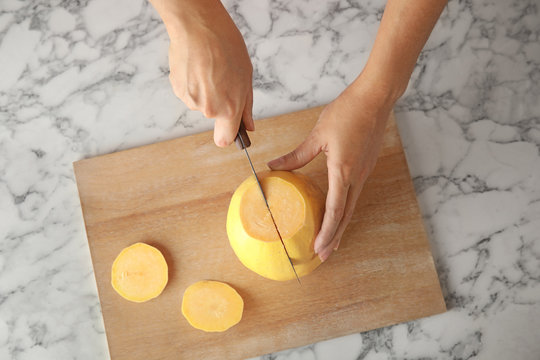 Woman Cutting Ripe Spaghetti Squash On Marble Table, Top View