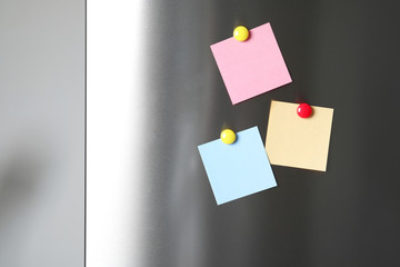 Blank notes with colorful magnets on refrigerator door. Space for text