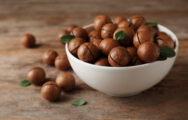 Bowl with organic Macadamia nuts and space for text on wooden background