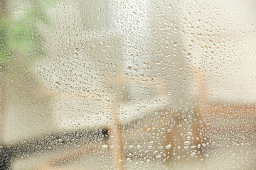 Blurred view of room through glass with water drops, closeup