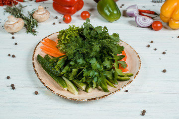 Fresh salad on brown plate on white textured table with cherry tomatoes and chilli and pepper spices and green at background