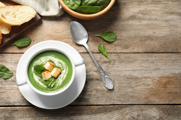 Flat lay composition with fresh vegetable detox soup made of spinach with croutons in dish and space for text on wooden table