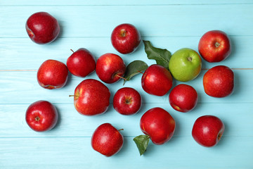 Naklejka na ściany i meble Green apple among red ones on wooden background, top view. Be different