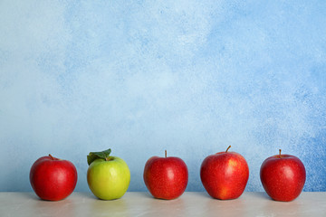 Row of red apples with green one on table. Be different