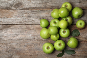 Many juicy green apples and space for text on wooden background, top view