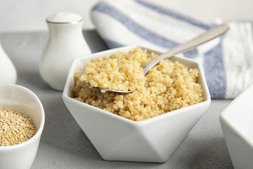 Composition with cooked quinoa in white ceramic bowl on table
