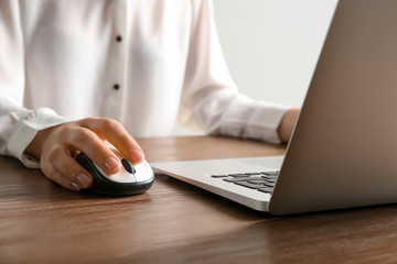 Woman using computer mouse with laptop at table, closeup
