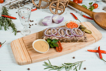 meat jelly traditional russian food on a wood plate on white table with spices and chilli and green on background