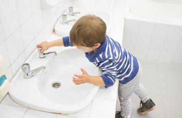3 years boy washing hands at adapted school sink