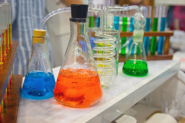 Laboratory glassware with solutions of different colors on table. Science