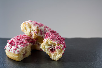 Donut with white frosting and pink sprinkles cut in half