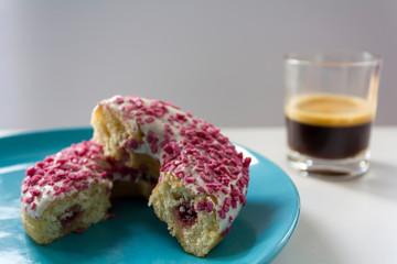 Delicious Glazed Donut with strawberry filling cut in half and a cup of black coffee