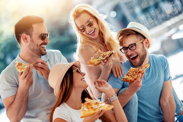 Close-up of four young cheerful people eating pizza